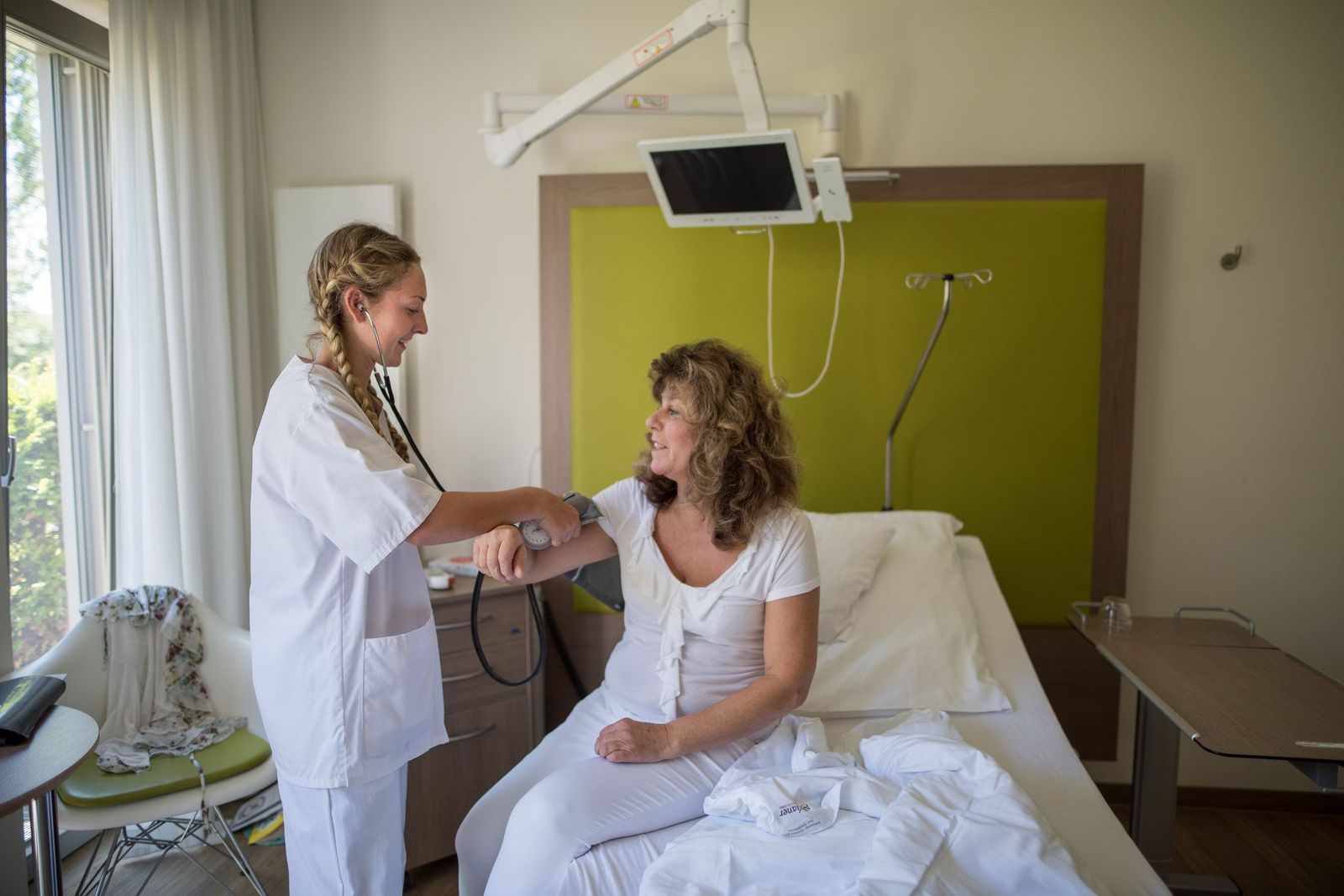 Krankenschwester misst Blutdruck einer Patientin am Krankenbett