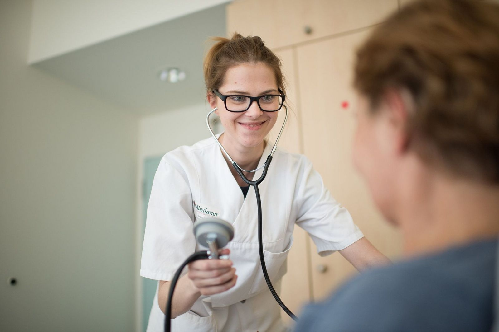 Junge Krankenschwester misst den Blutdruck bei einer Patientin
