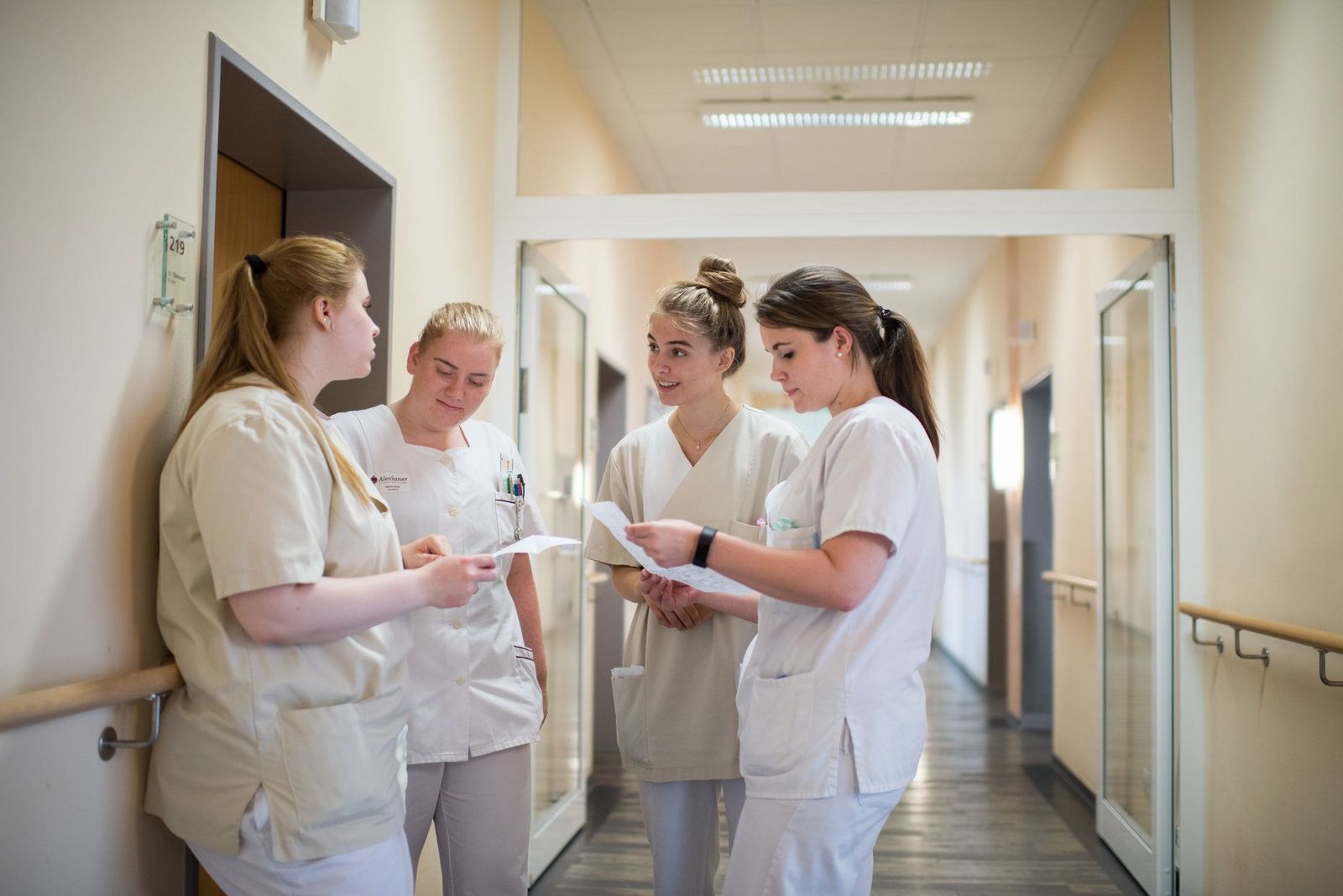 Vier junge Krankenschwestern im Austausch auf dem Stationsflur