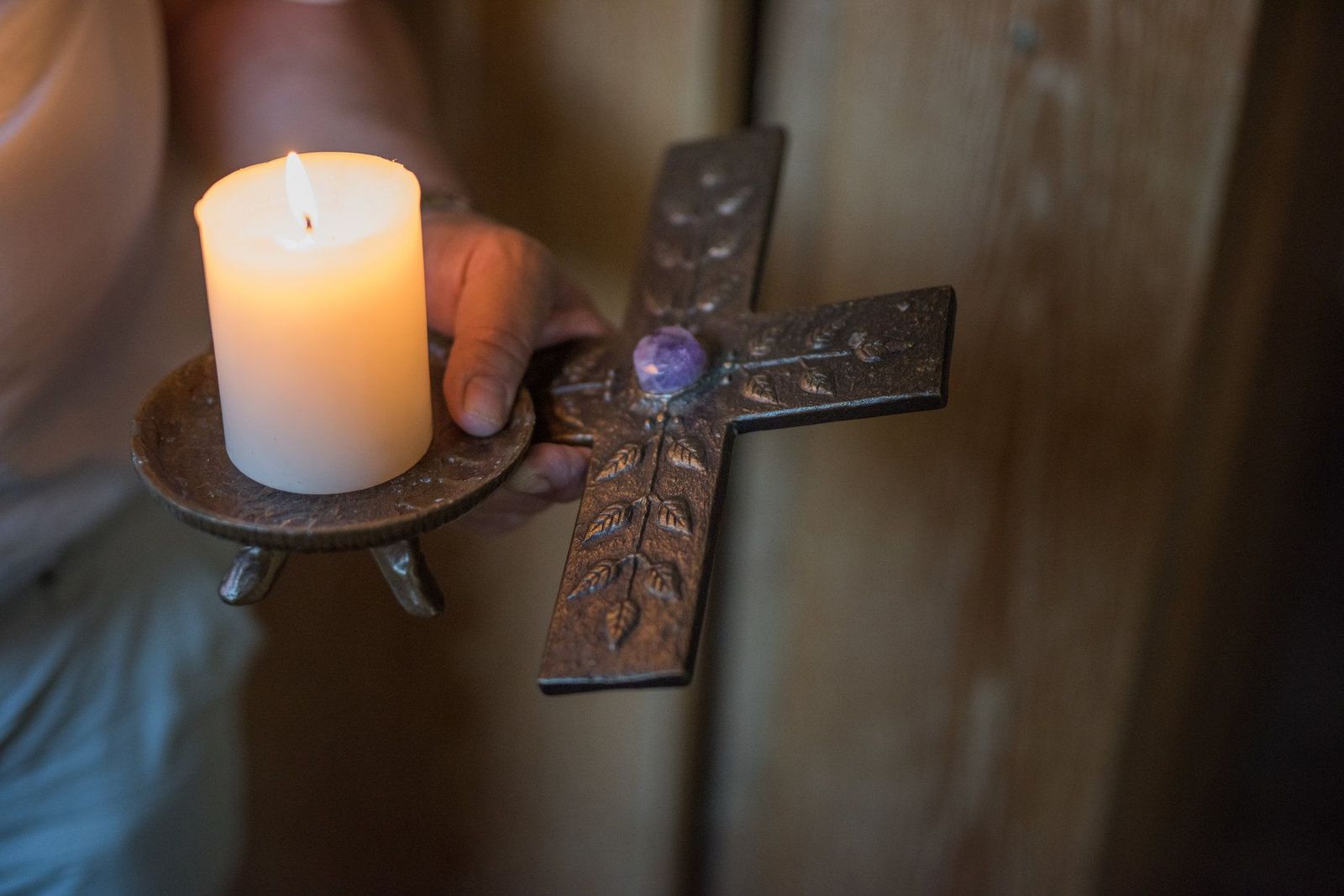 Seelsorger hält Kerze und Kreuz in der Hand