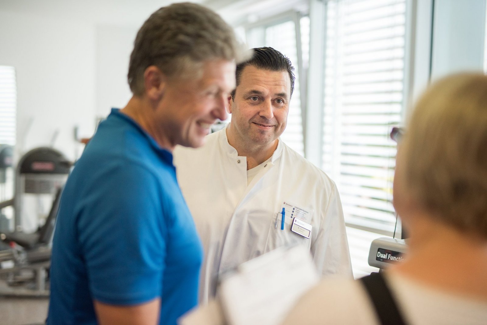 Arzt im Gespräch mit Rehapatient und Physiotherapeutin während der Physiotherapie Arzt im Gespräch mit Rehapatient und Physiotherapeutin während der Physiotherapie