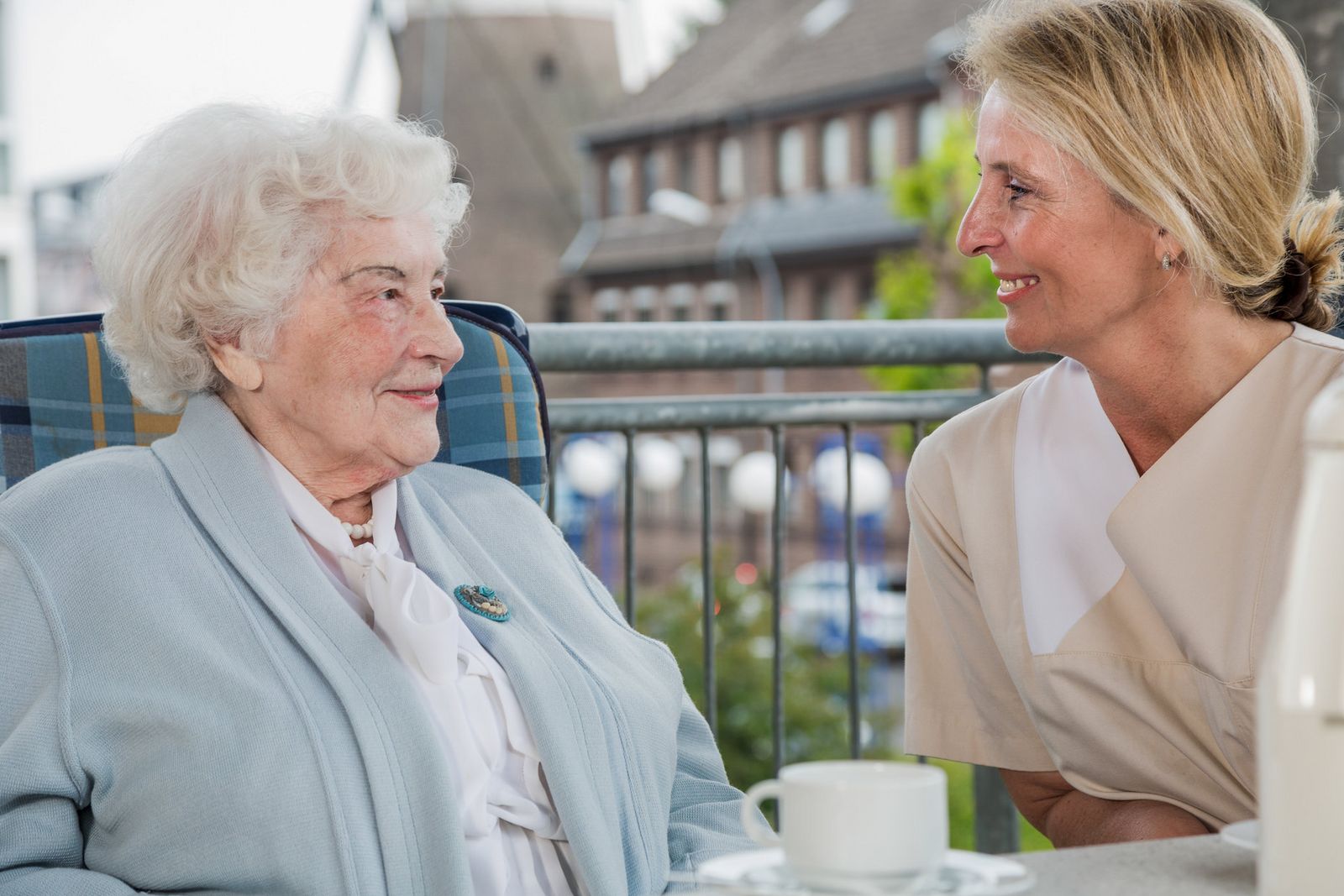 Pflegerin und ältere Dame im Gespräch am Balkon