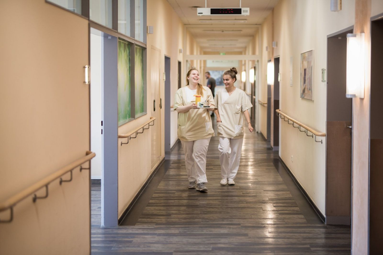 Zwei lachende junge Krankenschwestern auf den Weg ins Patientenzimmer