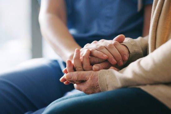 Pflegerin hält Hand einer Patientin